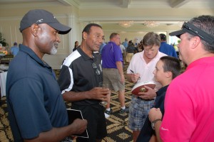 Washington Redskins alumni Mike Nelms, Roy Jefferson and Mike Bragg sign a football for Destination Cellars CEO David Keuhner and his son Jaden 