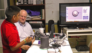 Tom Meeks watches Jimmy Escobar try a haptic device, which provides an artificial sense of touch in making 3D designs