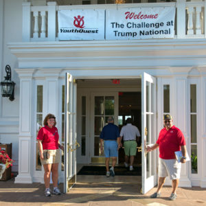 Volunteers Una Murphy and Steve Levenson welcome guests to YouthQuest's Challenge at Trump National Golf Club