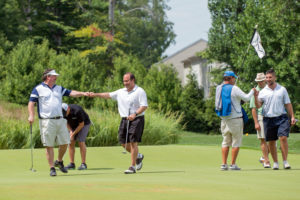 Players celebrate a putt at YouthQuest's Challenge at Trump National Golf Club on August 8, 2016