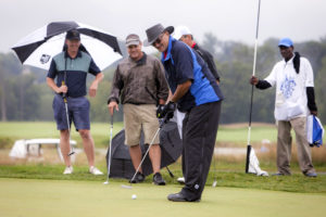 YouthQuest Co-Founder Allen Cage putts in the rain at the golf tournament August 7, 2017.