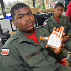 Capital Guardian Youth ChalleNGe Academy Cadet Kaya Green holds a 3D-printed e-Nable hand assembled during a Vocational Orientation tour of Local Motors National Harbor on April 19, 2018