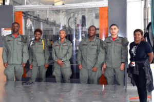 Local Motors National Harbor Customer Engagement Manager Tracye Johnson stands with 3D ThinkLink students from Capital Guardian Youth ChalleNGe Academy in front of a BAAM (Big Area Additive Manufacturing) machine 