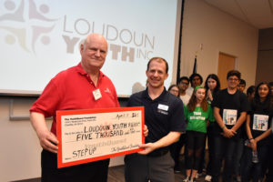 YouthQuest Director of Instruction Tom Meeks presents prize money check to Loudoun Youth CEO Jared Melvin at the Step Up Loudoun Youth Competition finals on April 11, 2019 at the Brambleton Library. 