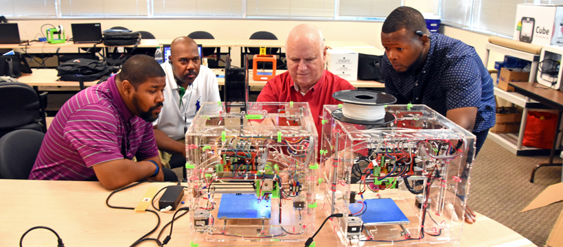 Freestate's Jonathan Brown, Capital Guardian's Keith Hammond, YouthQuest Director of Instruction Tom Meeks and Freestate's Jamarr Dennis work with a JellyBox 3D printer during 3D ThinkLink Teacher Training on Sept. 27, 2017.