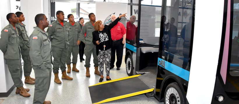 Customer Engagement Manager Tracye Johnson points to the 3D-printed Accessible Olli vehicle during a Vocational Orientation tour of Local Motors in National Harbor, Maryland for 3D ThinkLink students from DC's Capital Guardian Youth ChalleNGe Academy on April 19, 2018.